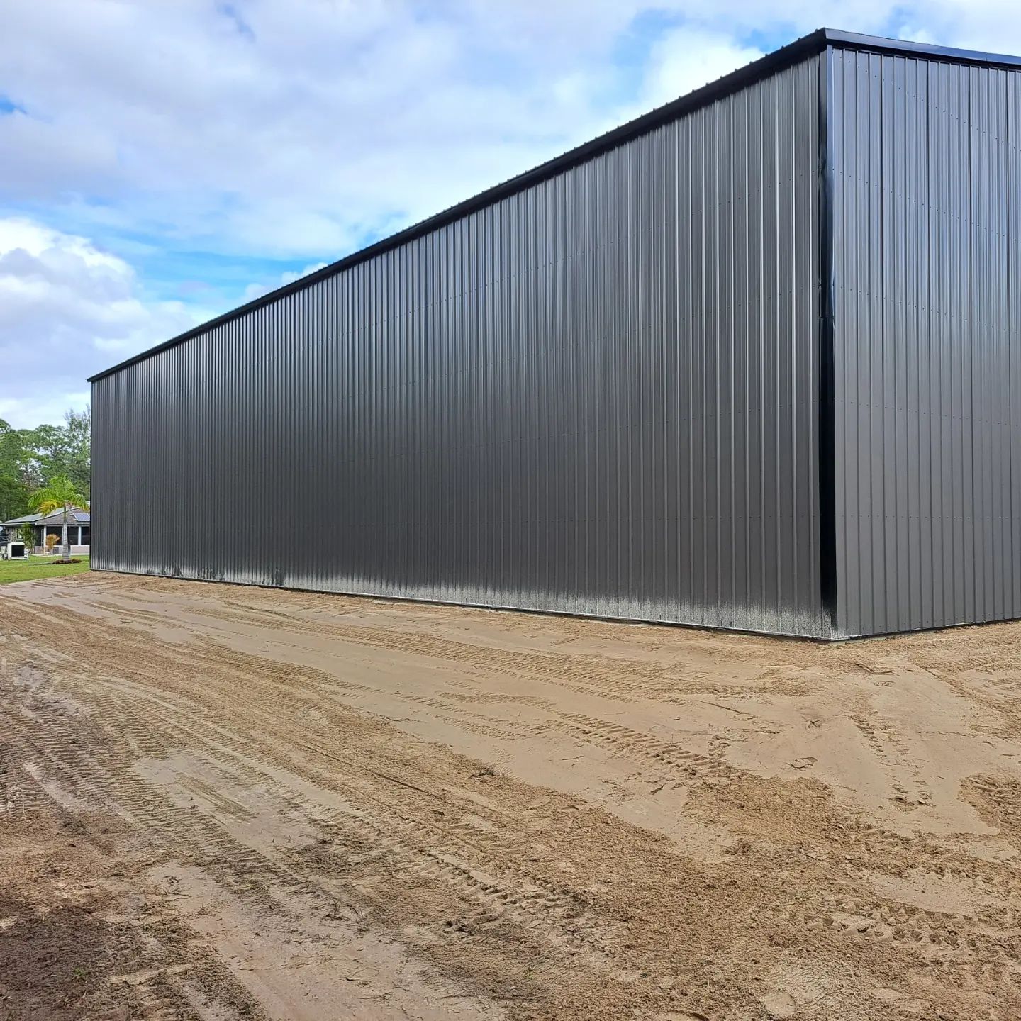 A large metal building is sitting in the middle of a dirt field.