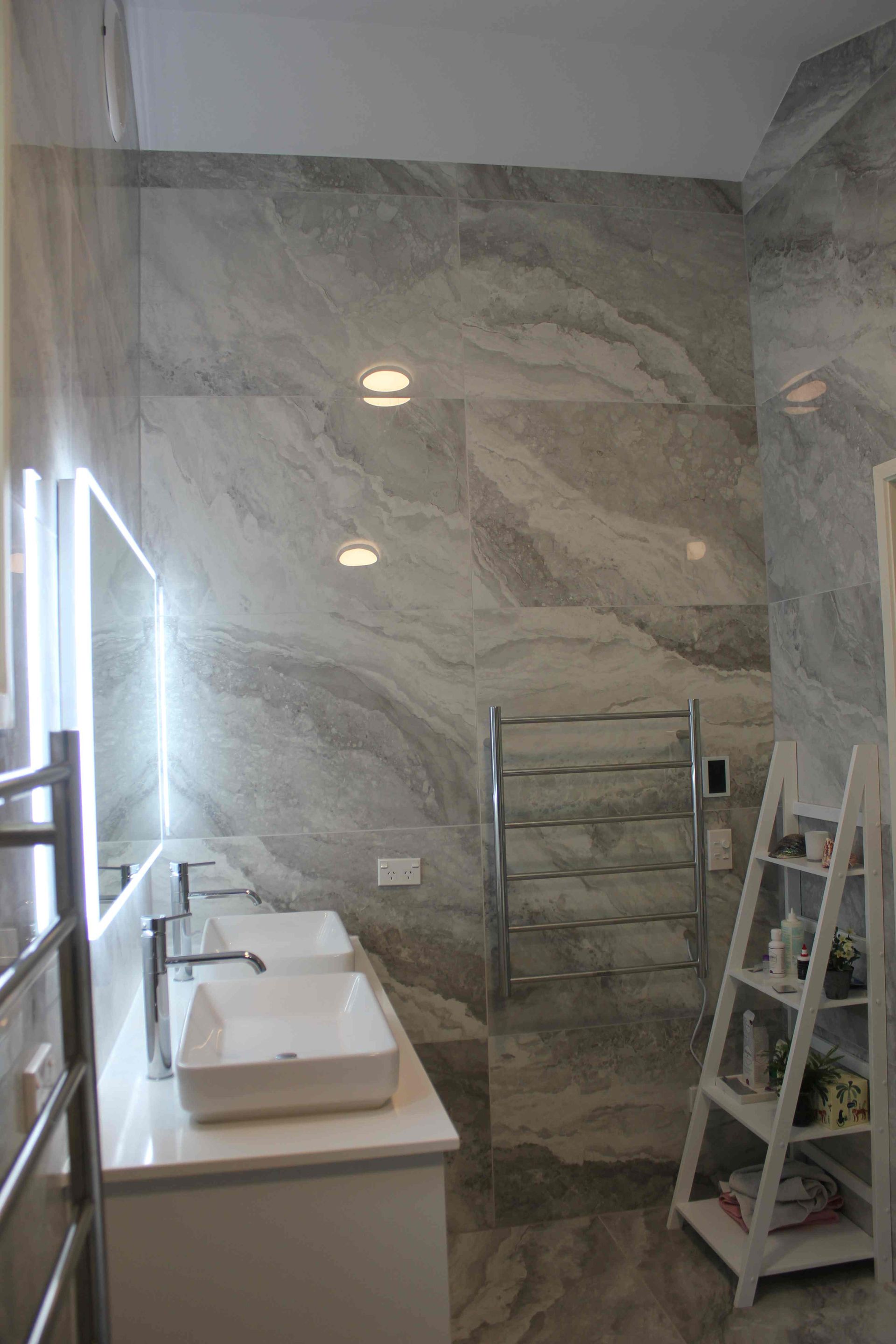 A bathroom with two sinks , a mirror and a ladder.