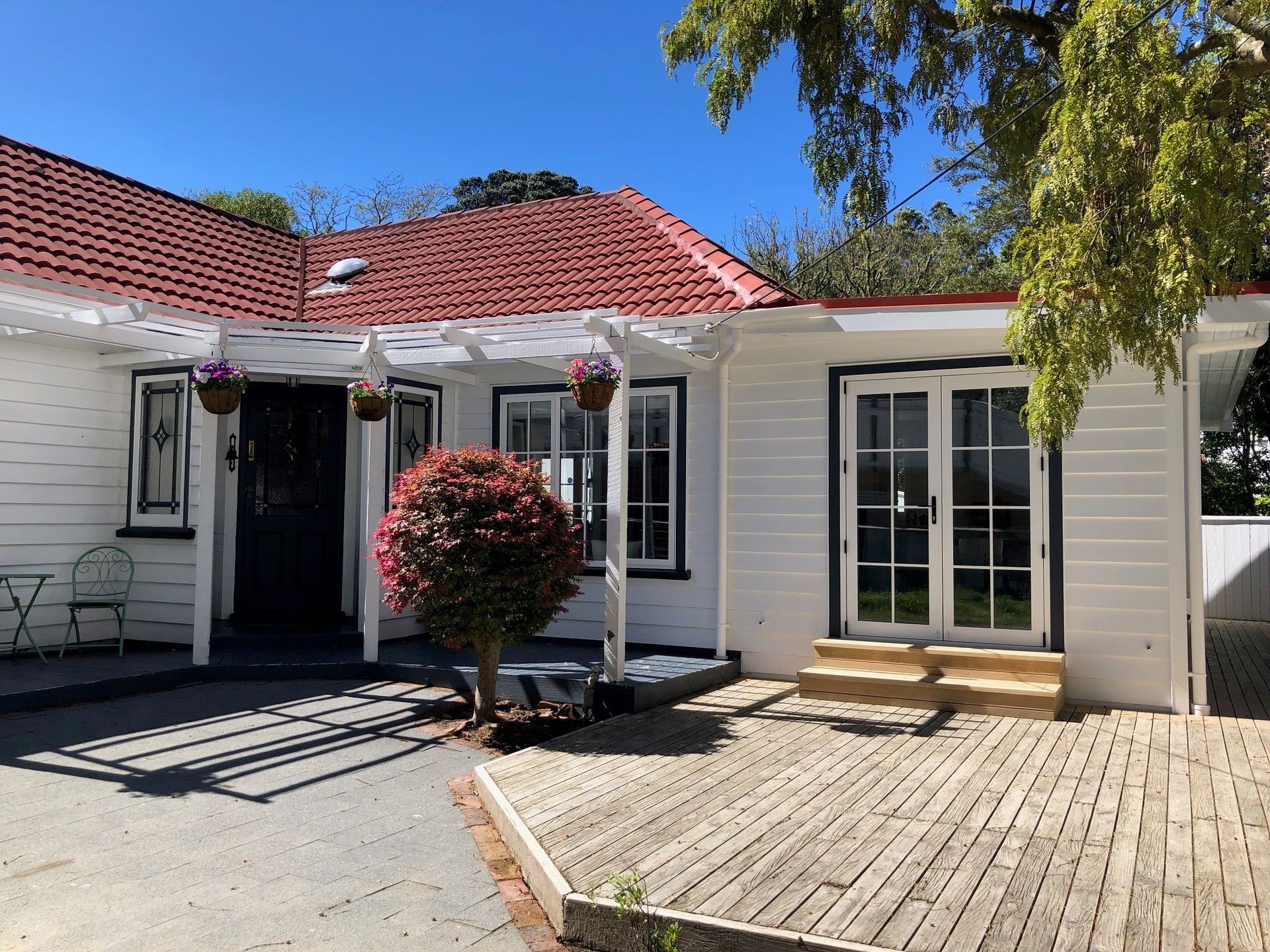 A white house with a red roof and a tree in front of it