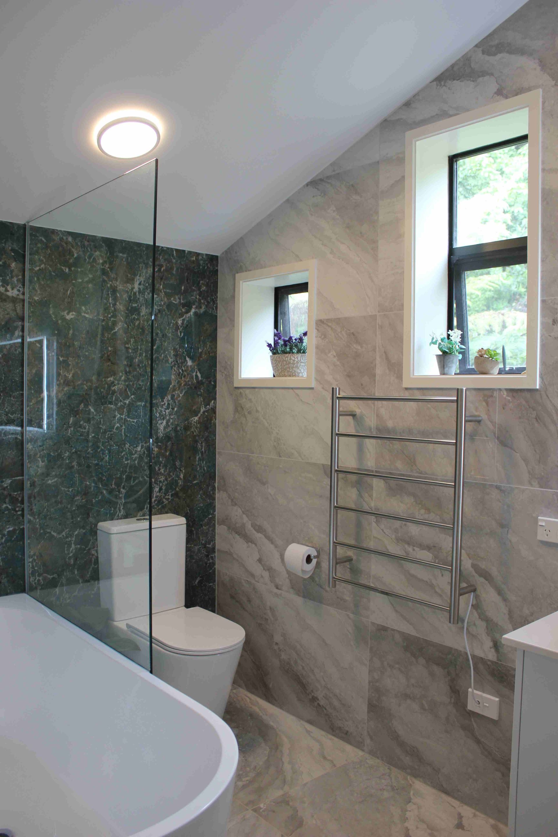 A bathroom with a toilet , tub , shower and window.