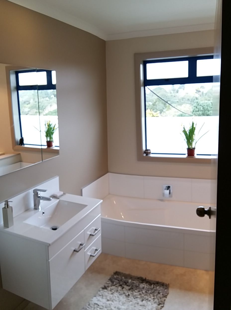 A bathroom with a sink , tub , mirror and window.