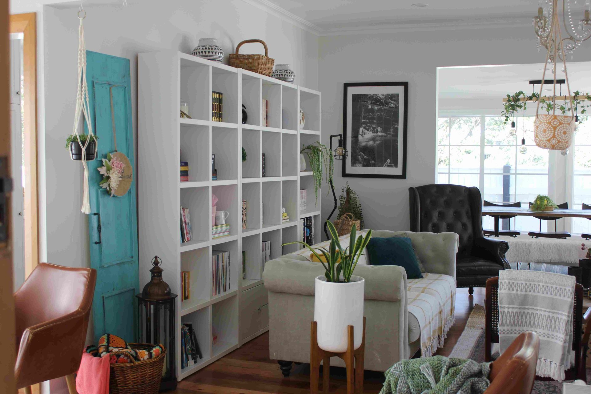 A living room with a couch , chairs , shelves and a blue door.