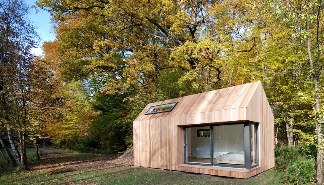 A small wooden house is sitting in the middle of a forest.