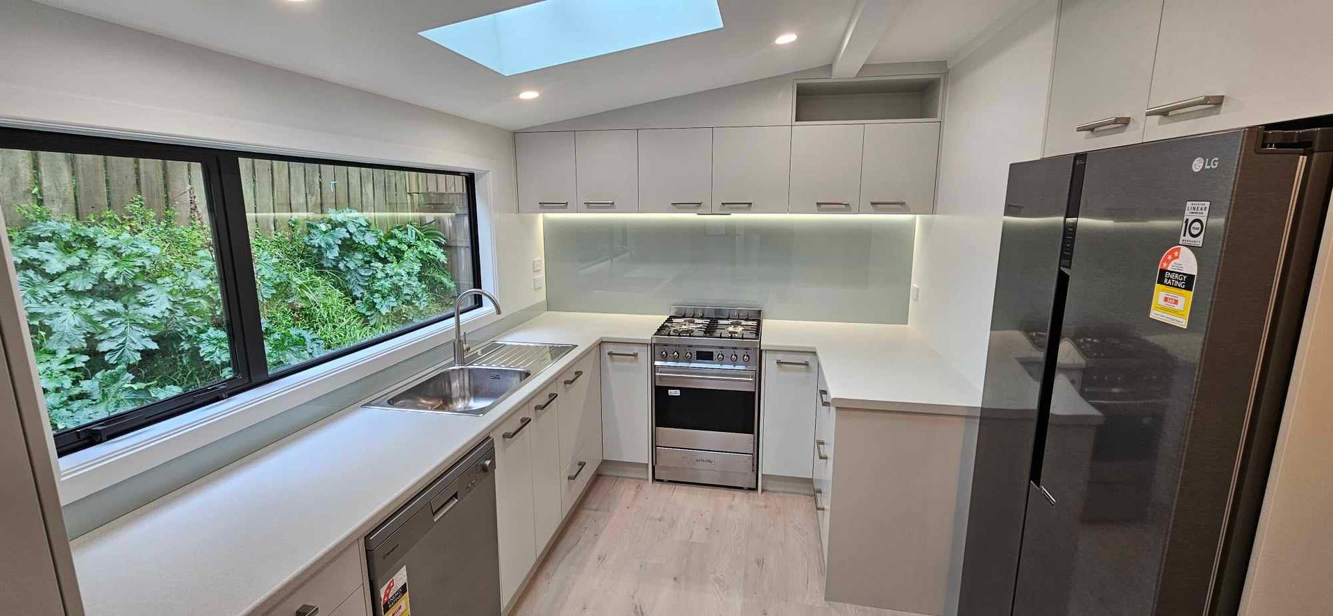 A kitchen with white cabinets , stainless steel appliances , a stove and a refrigerator.