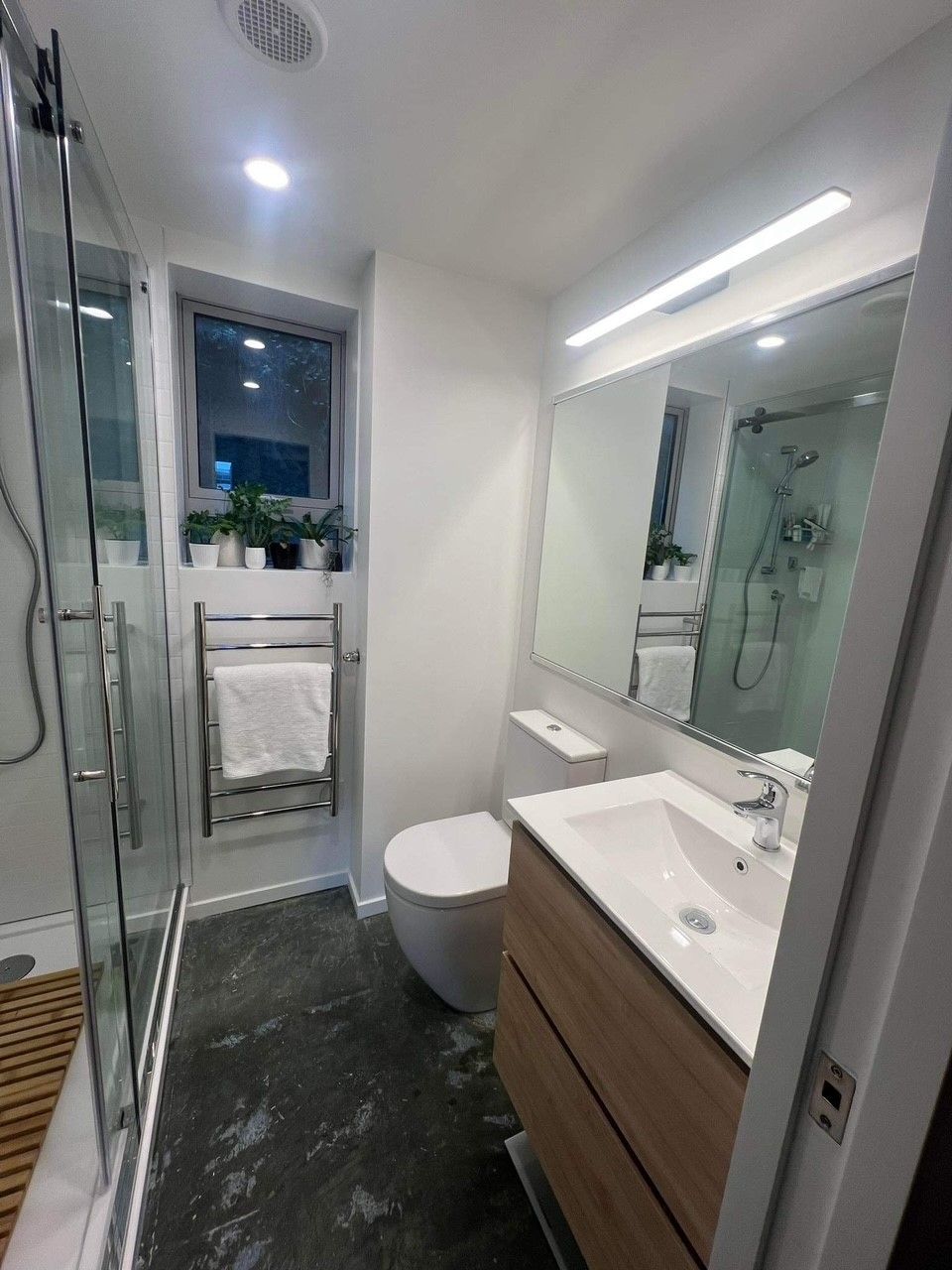 A bathroom with a toilet , sink , mirror and shower.