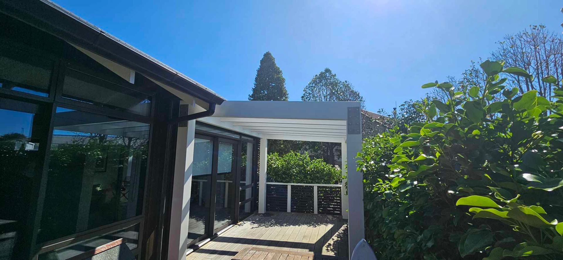 A house with a pergola in the backyard on a sunny day.