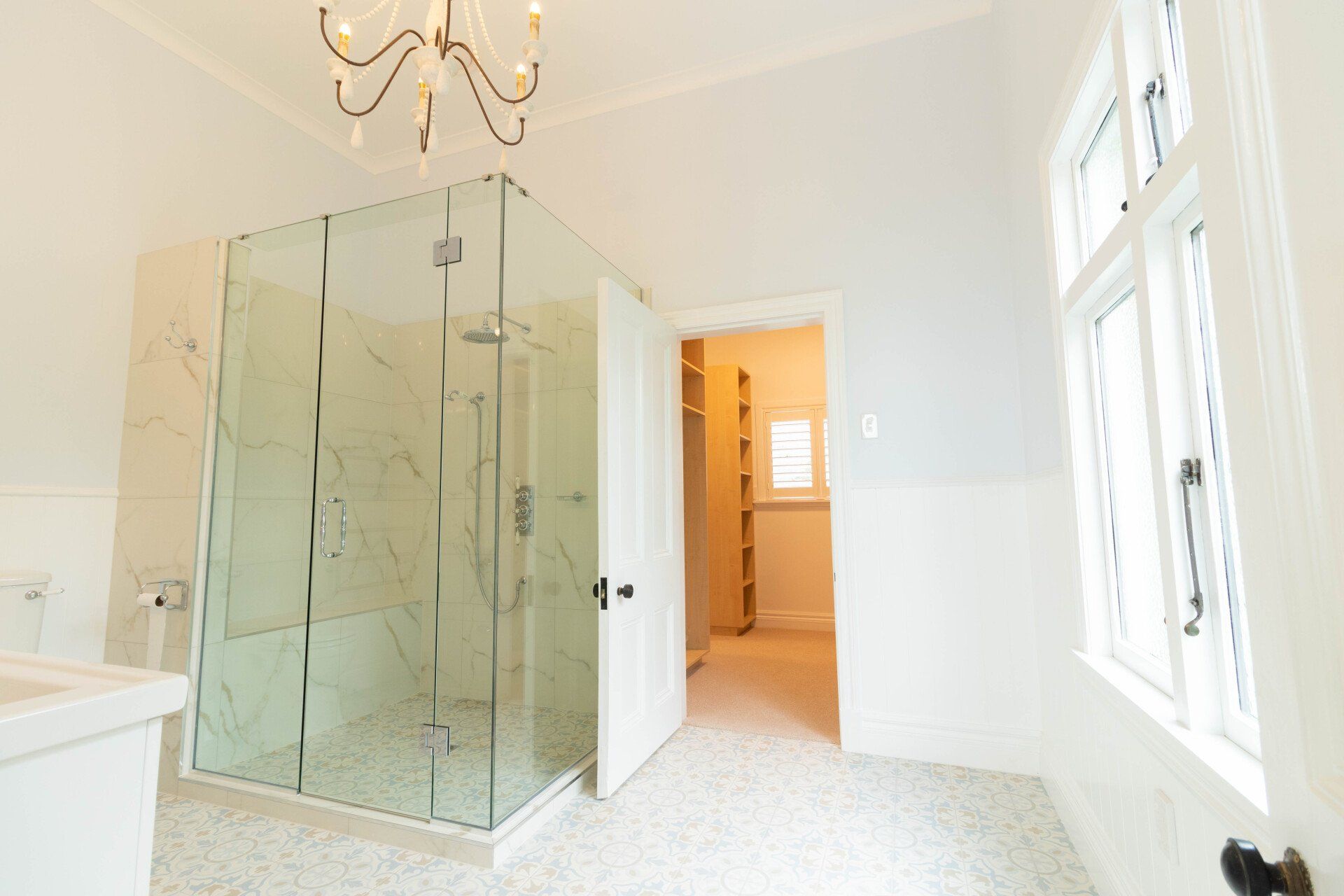 A bathroom with a walk in shower and a chandelier hanging from the ceiling.