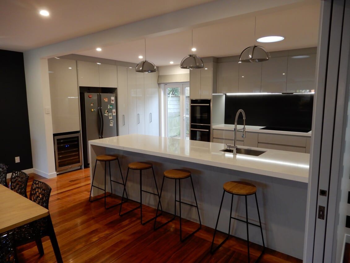 A kitchen with a large island , stools , a table and a refrigerator.