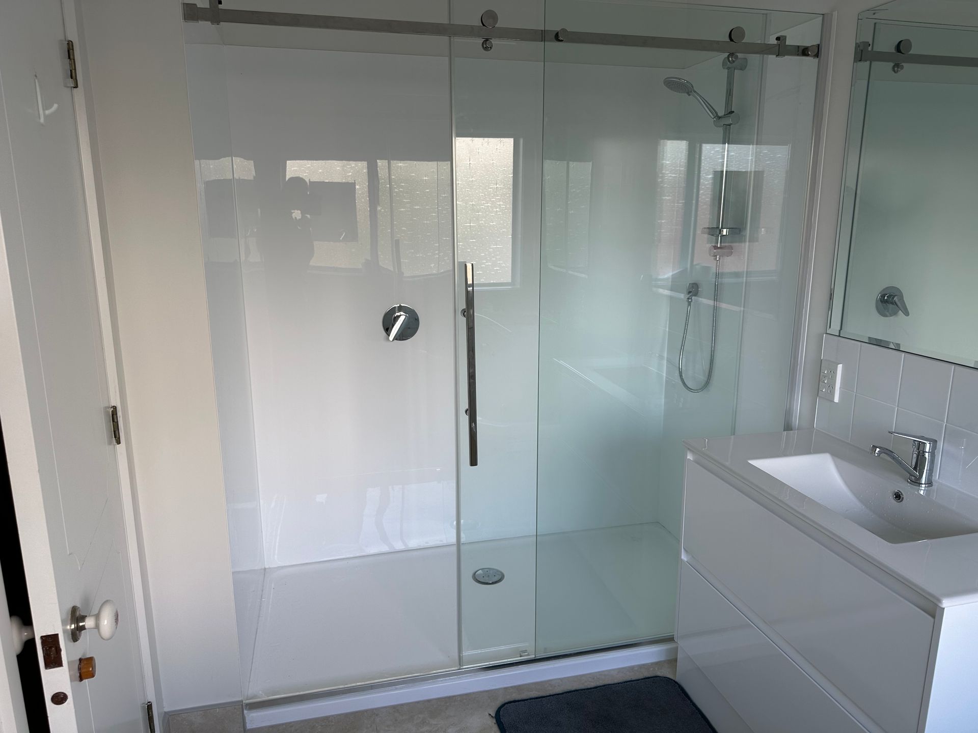 A bathroom with a sliding glass shower door and a sink.