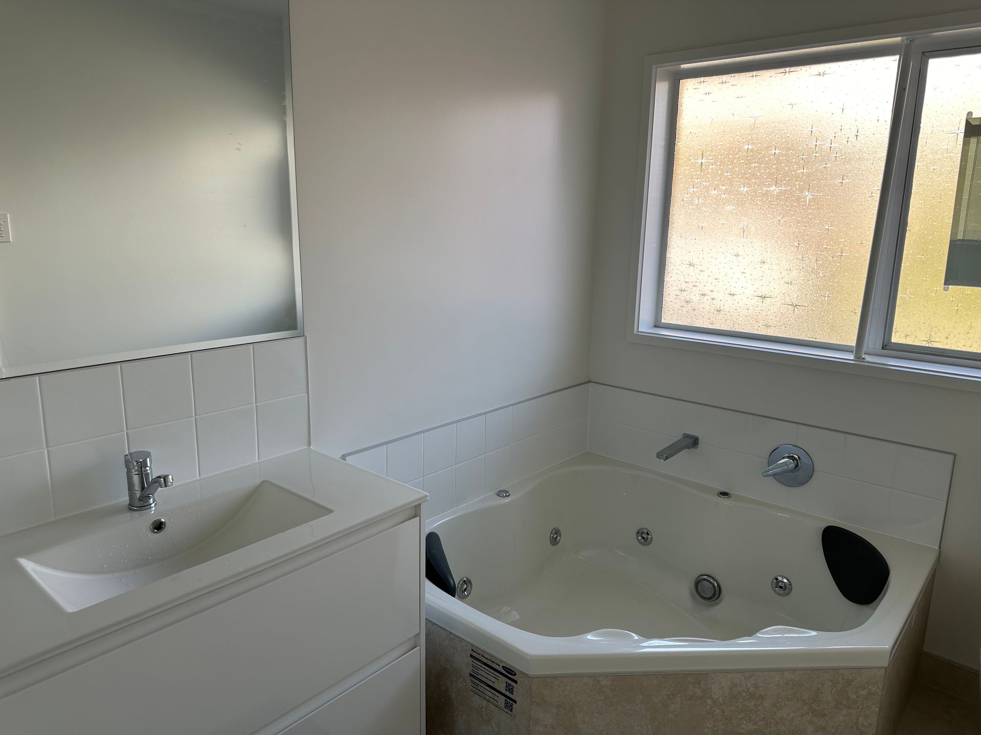 A bathroom with a jacuzzi tub , sink and mirror.