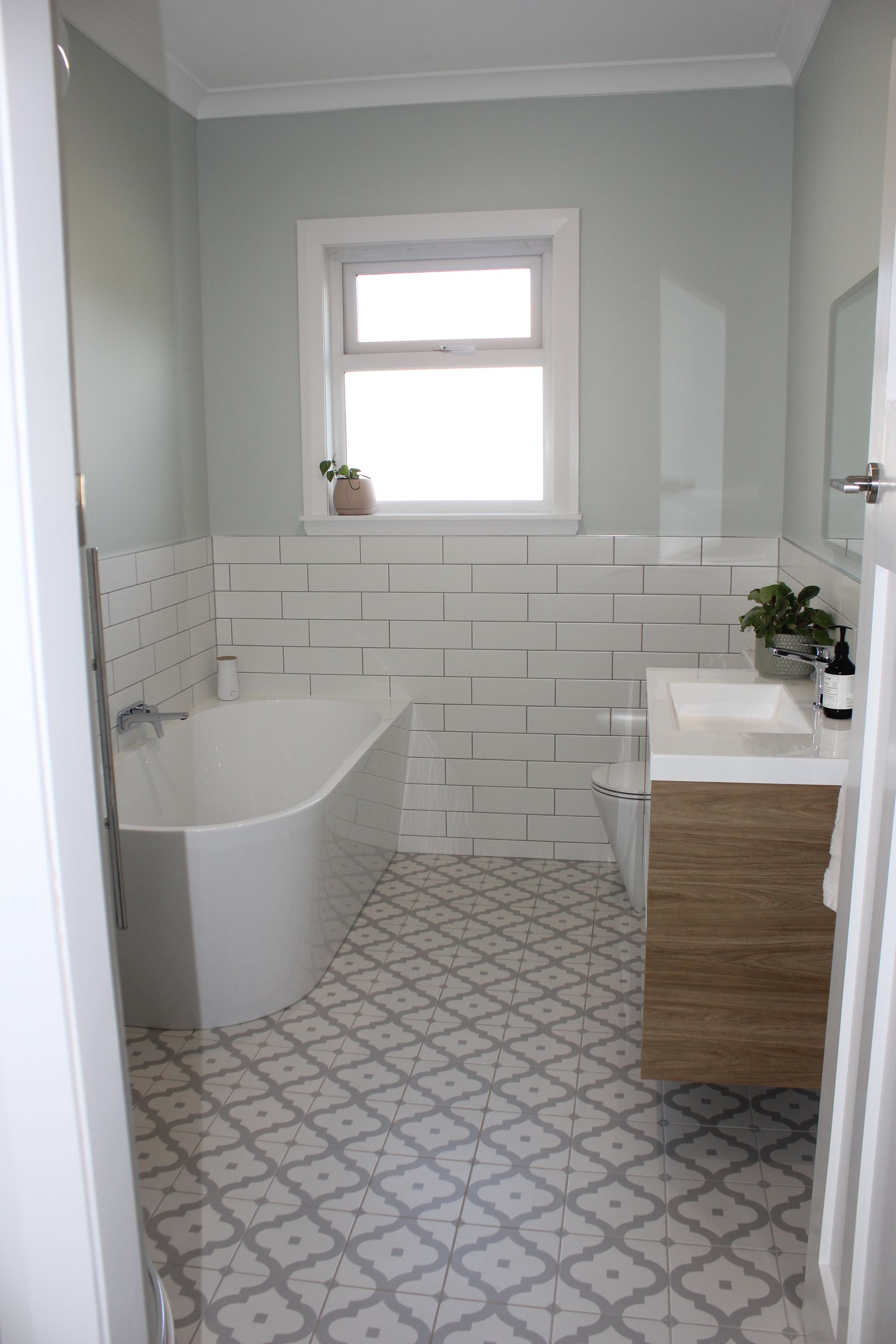 A bathroom with a bathtub , sink , and window.