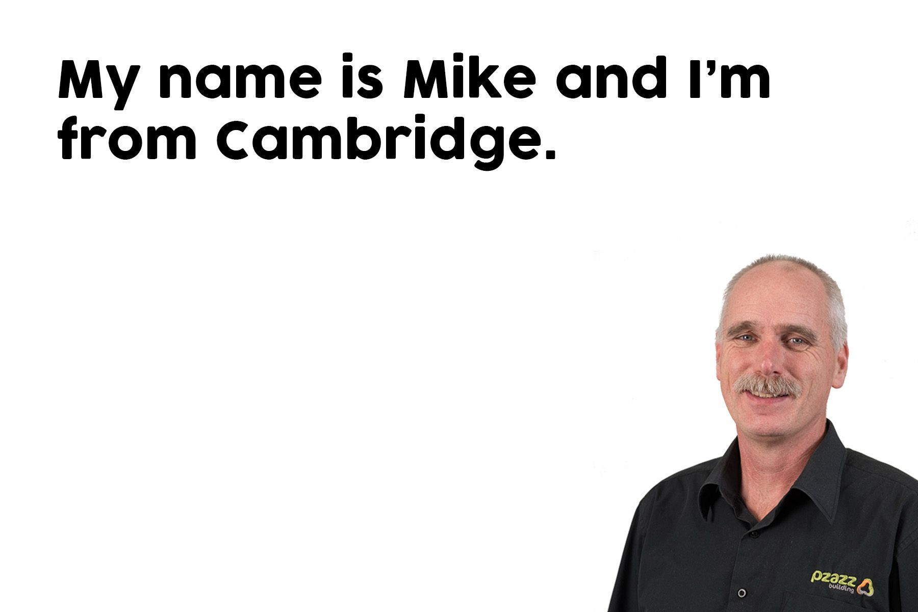 A man is standing in front of a white background with the words `` my name is mike and i 'm from cambridge . ''