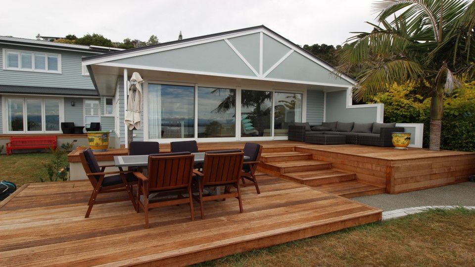 A wooden deck with a table and chairs in front of a house.