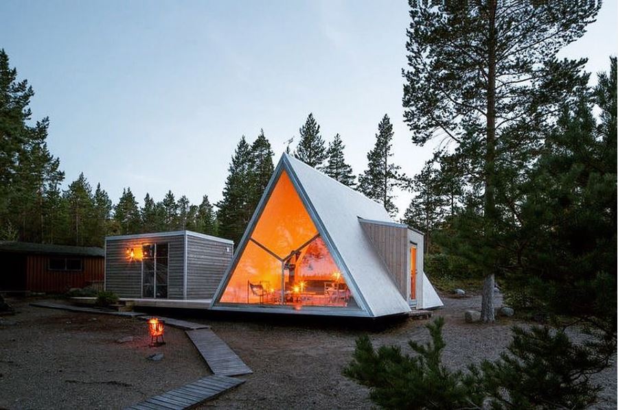 A triangle shaped house in the middle of a forest