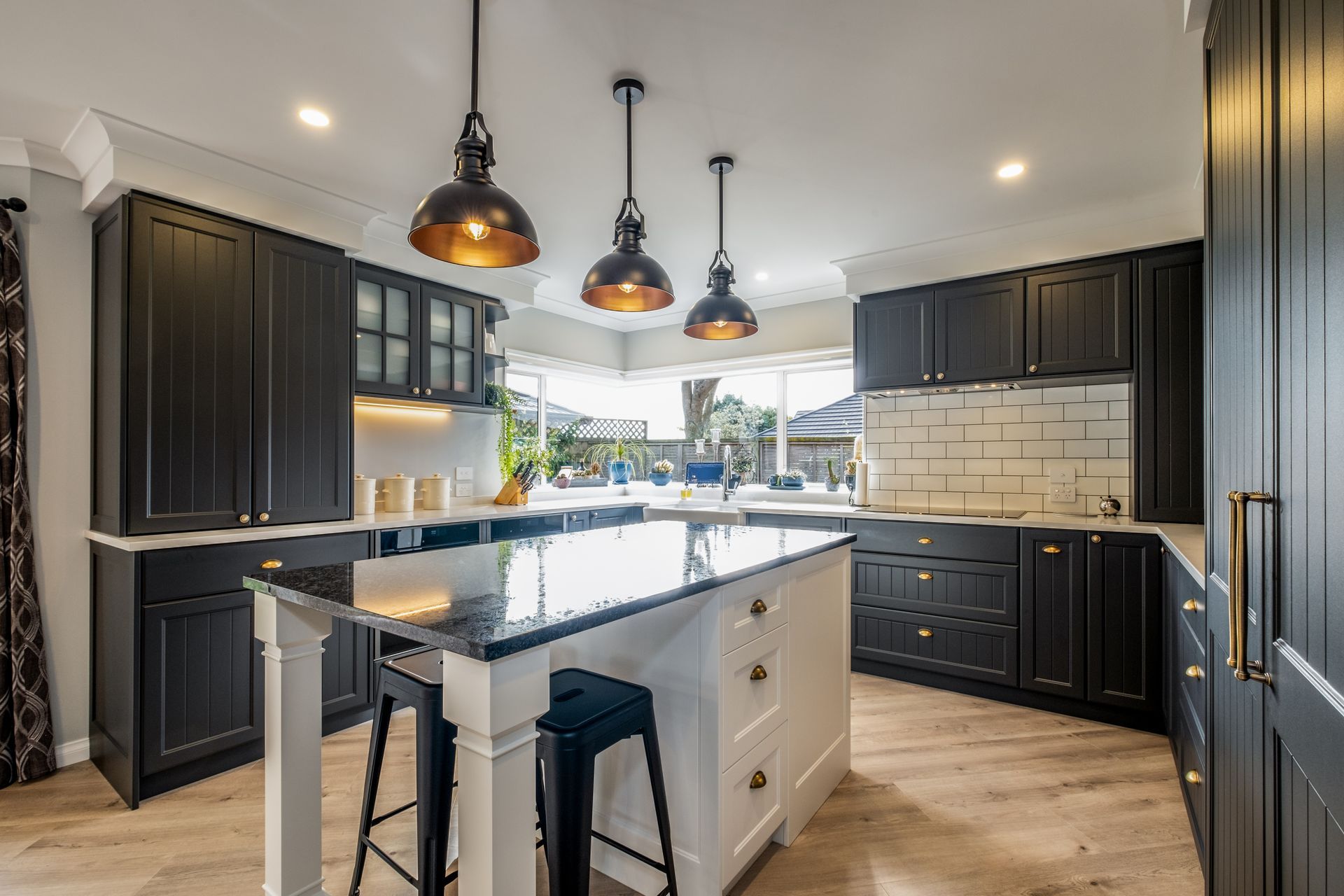 A kitchen with black cabinets and a large island in the middle.