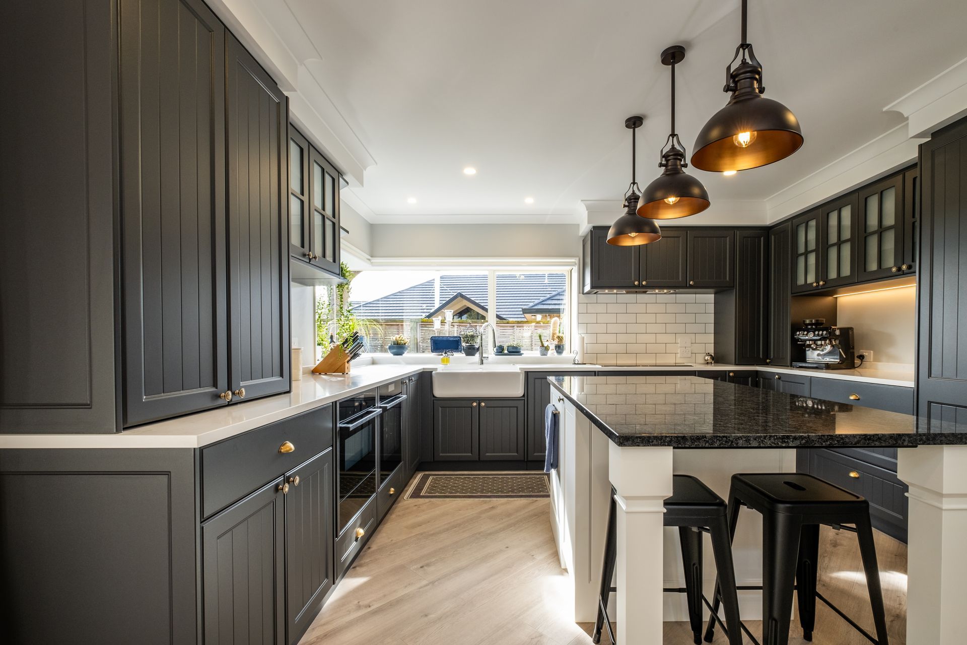 A kitchen with black cabinets , granite counter tops , stools and a large island.