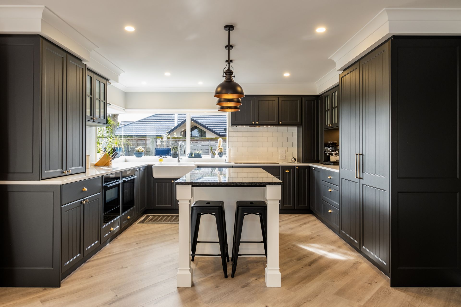 A kitchen with black cabinets and a large island in the middle.