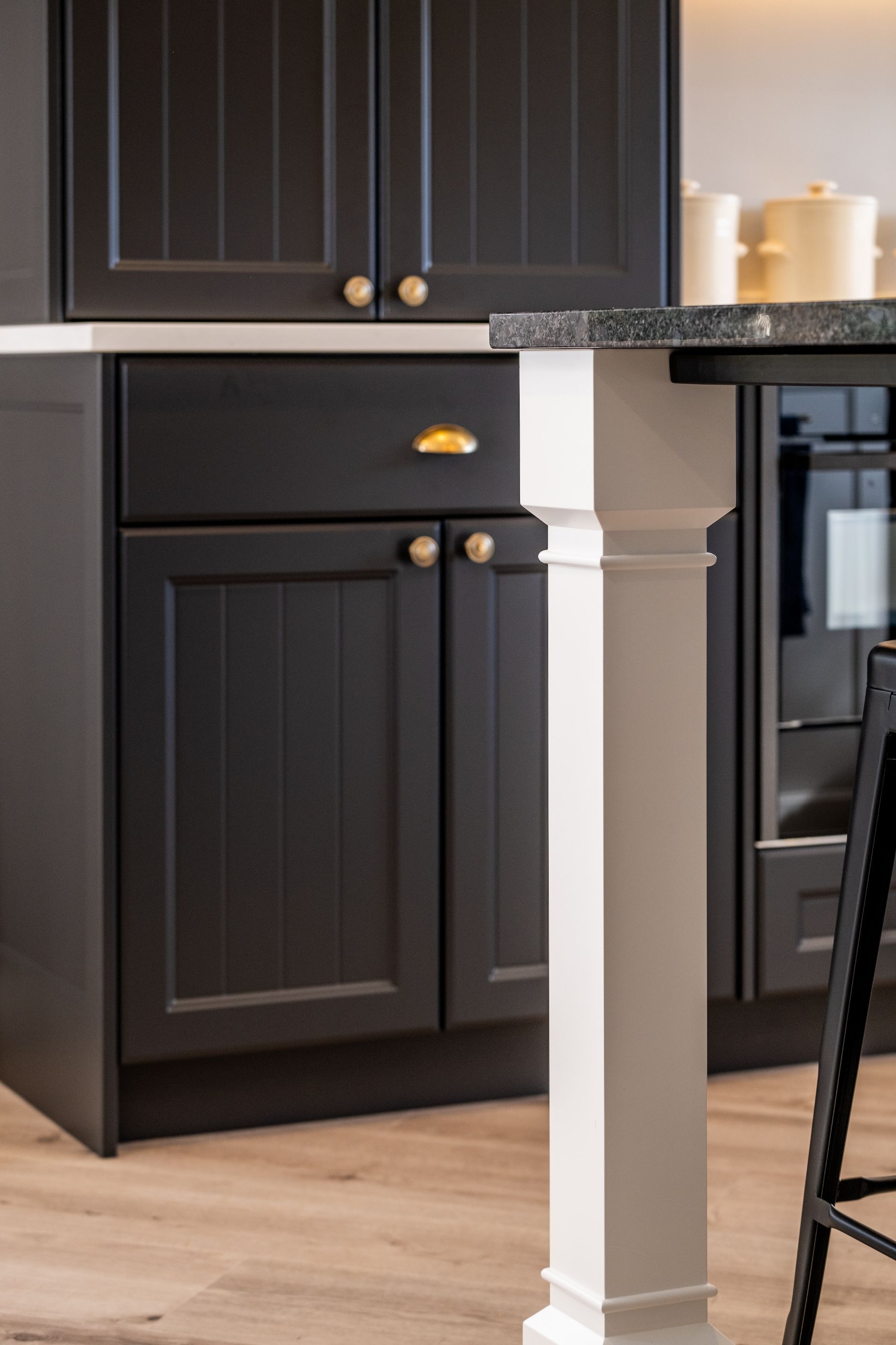 A kitchen with black cabinets and a white table.