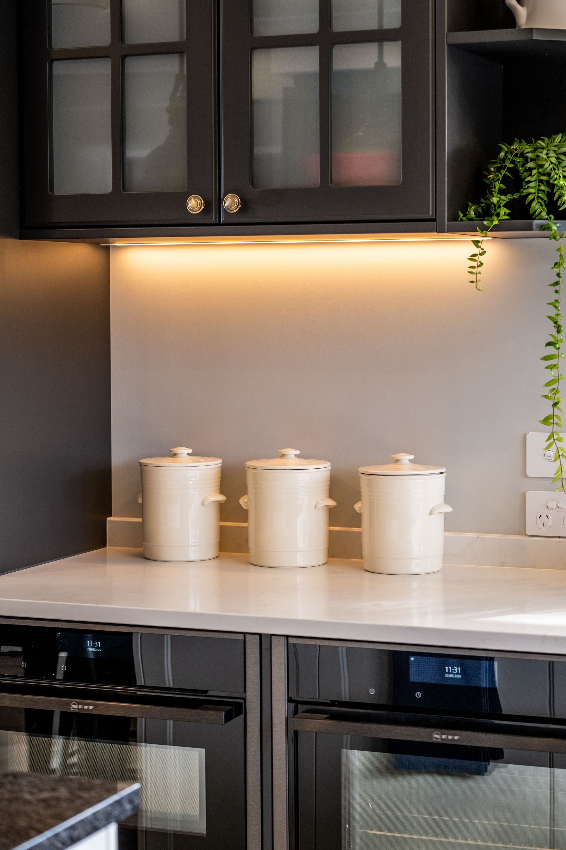 Three white pots are sitting on a counter in a kitchen.