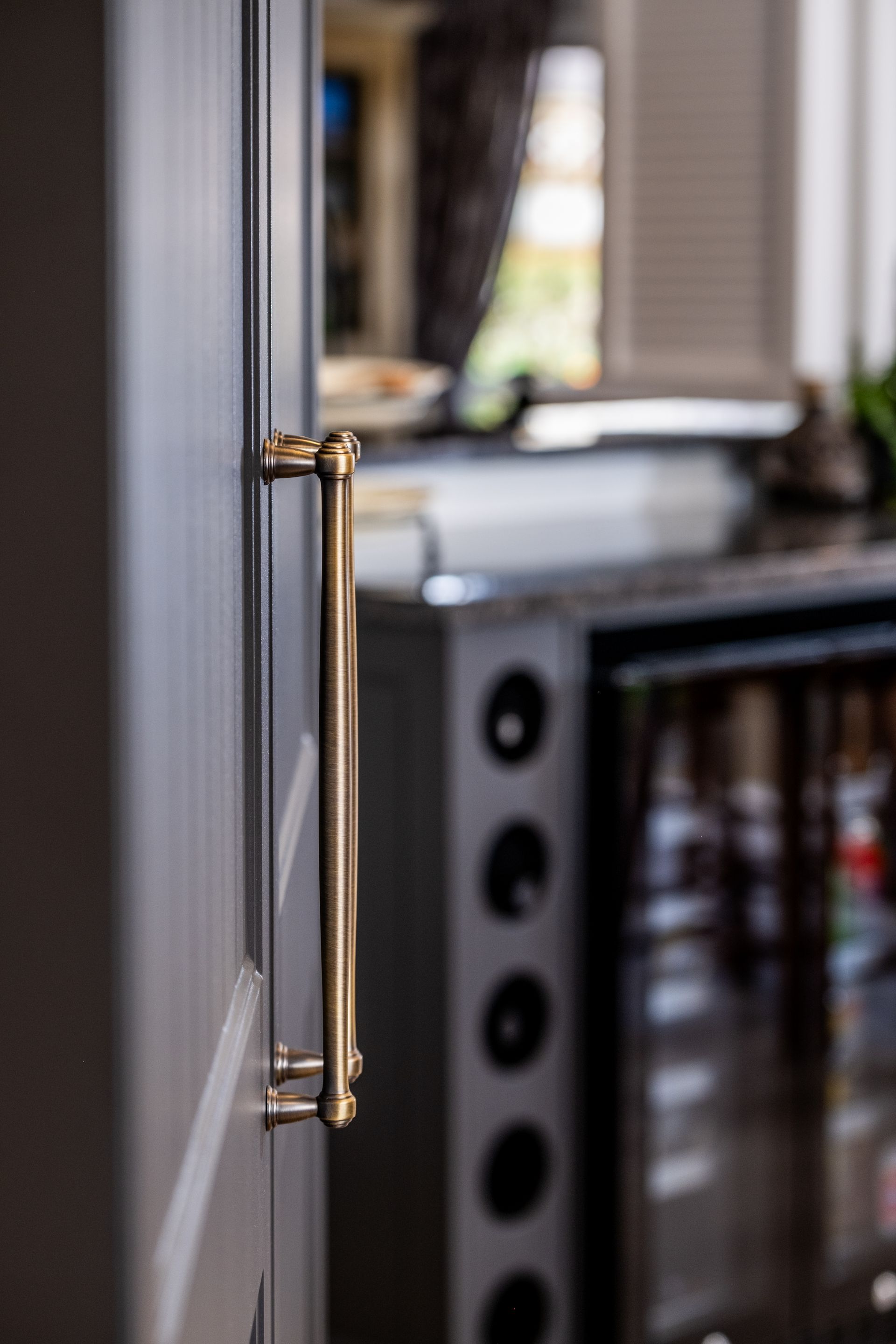 A close up of a brass handle on a refrigerator door in a kitchen.