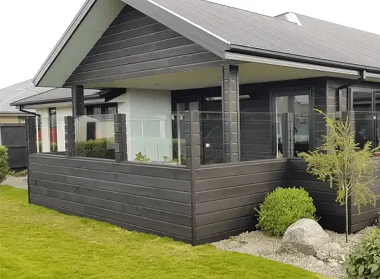 A small house with a large porch and a glass railing.