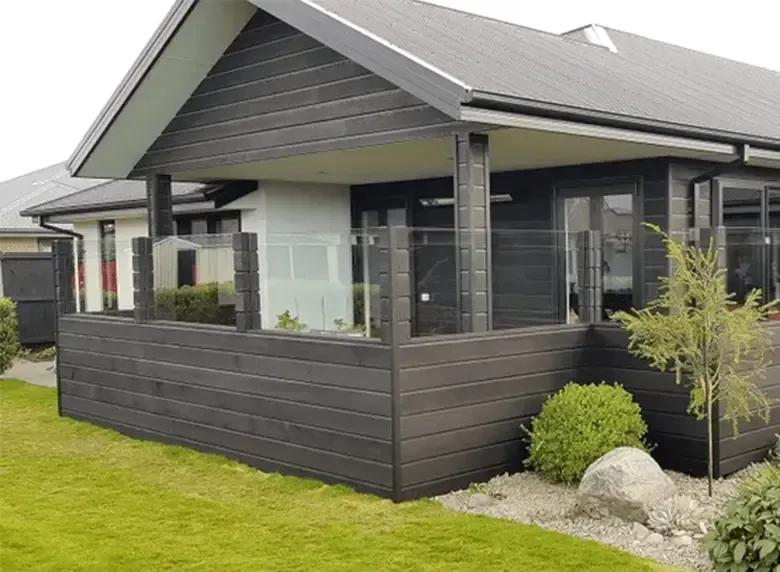 A small house with a large porch and a glass railing.