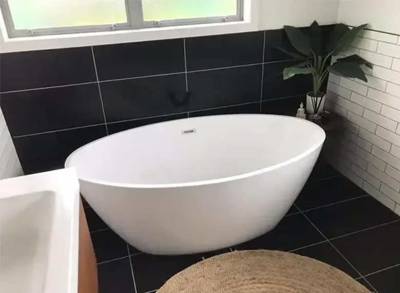 A white bathtub is sitting in a bathroom next to a window.