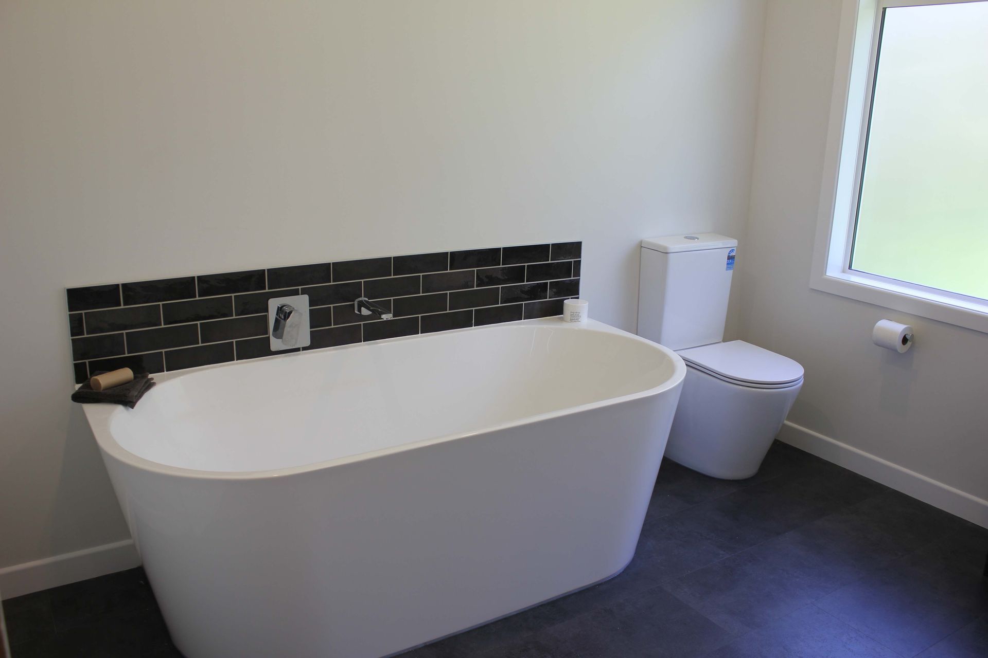 A bathroom with a bathtub , toilet and window.