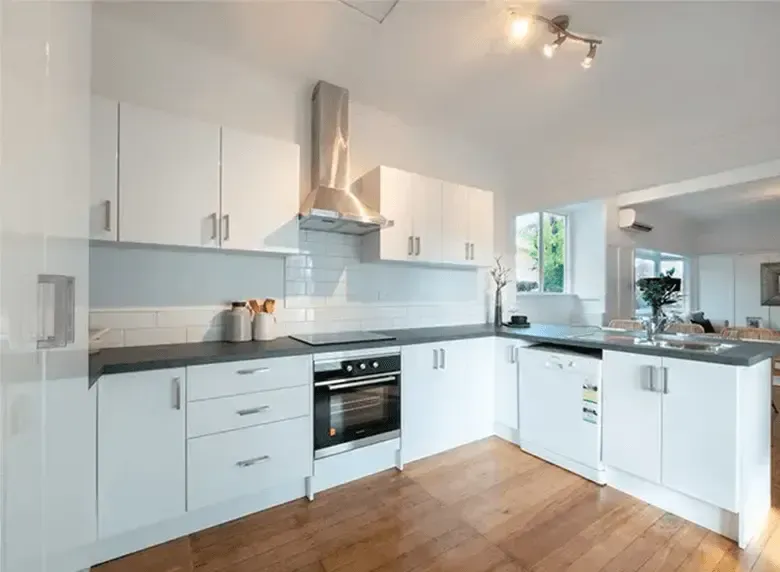 A kitchen with white cabinets and wooden floors