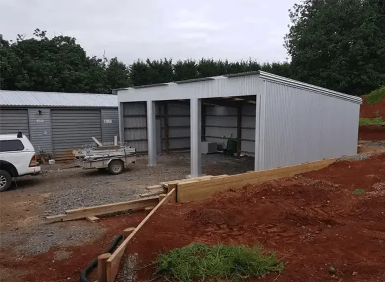 A white truck is parked in front of a garage under construction.