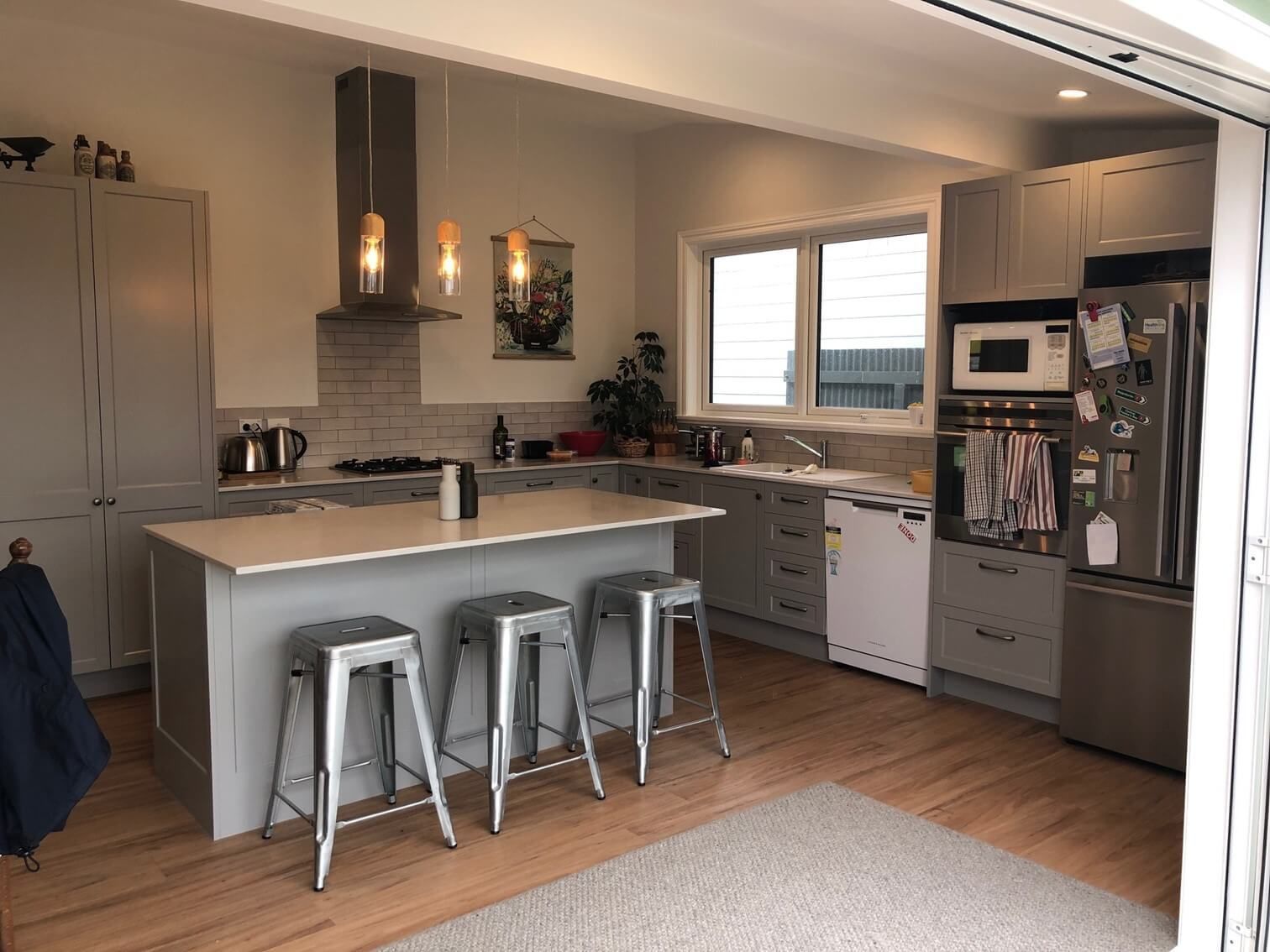 Modern bathroom with a white freestanding tub, a wood vanity with a vessel sink, and gray tiled walls and floor.