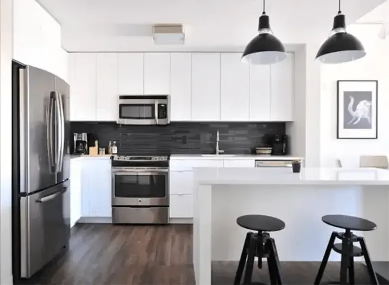 A kitchen with white cabinets , stainless steel appliances , a refrigerator and a microwave.