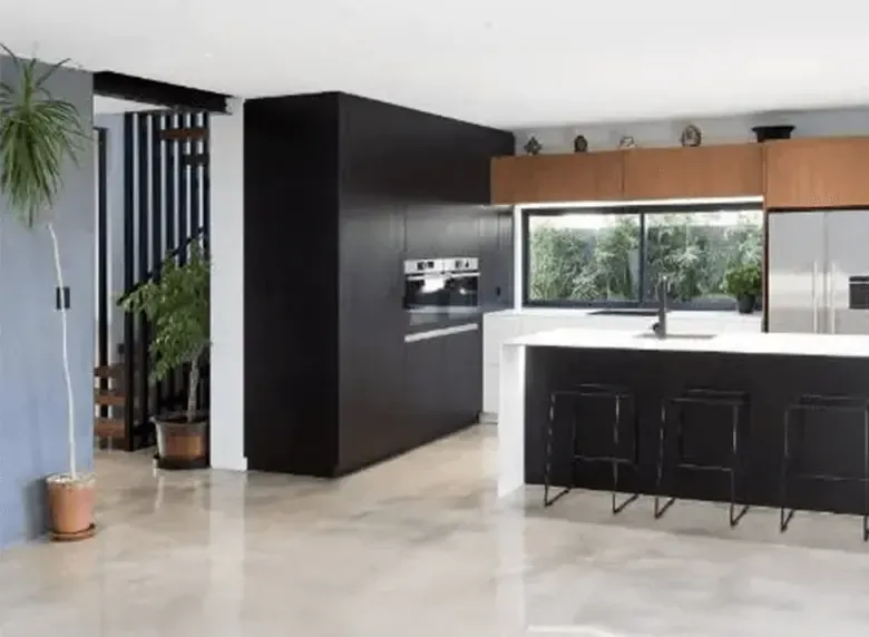 A kitchen with black cabinets , stainless steel appliances , and a large island.