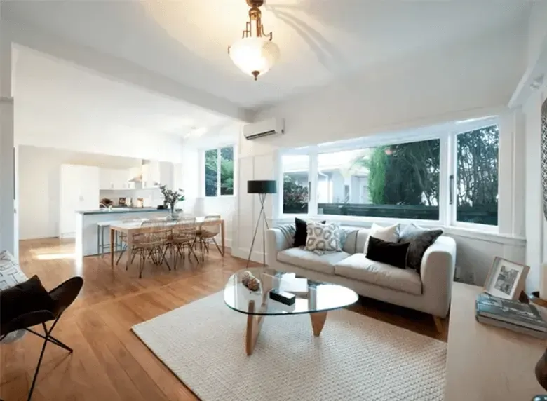 A living room with a white couch and a glass coffee table