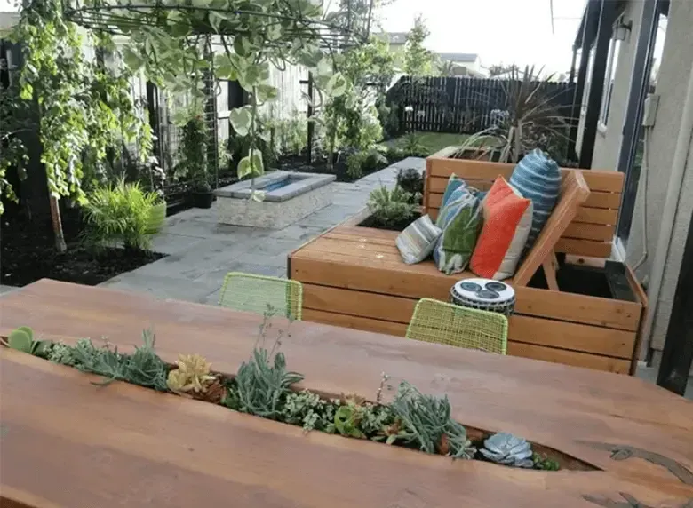 A wooden table with plants growing out of it in a garden.