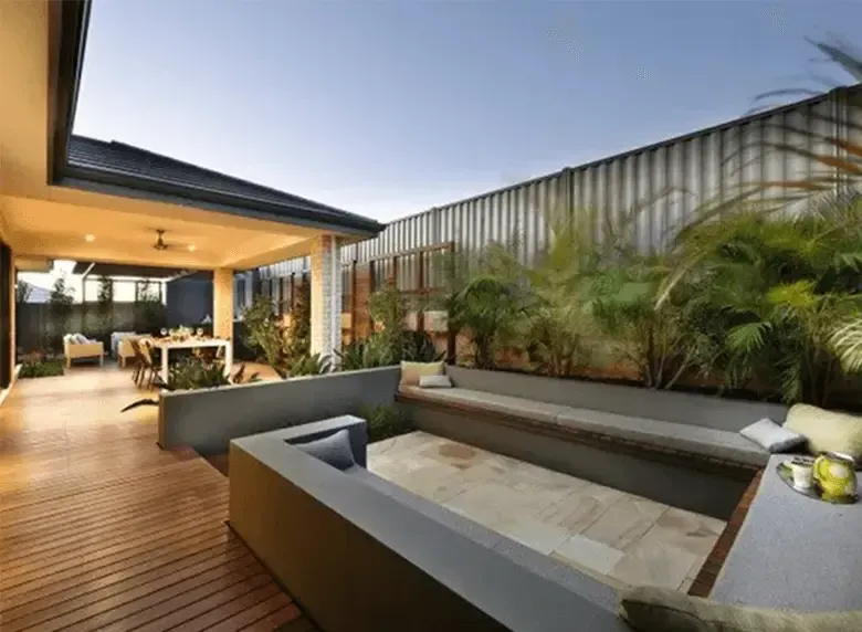 A wooden deck with a couch and a table in the backyard of a house.