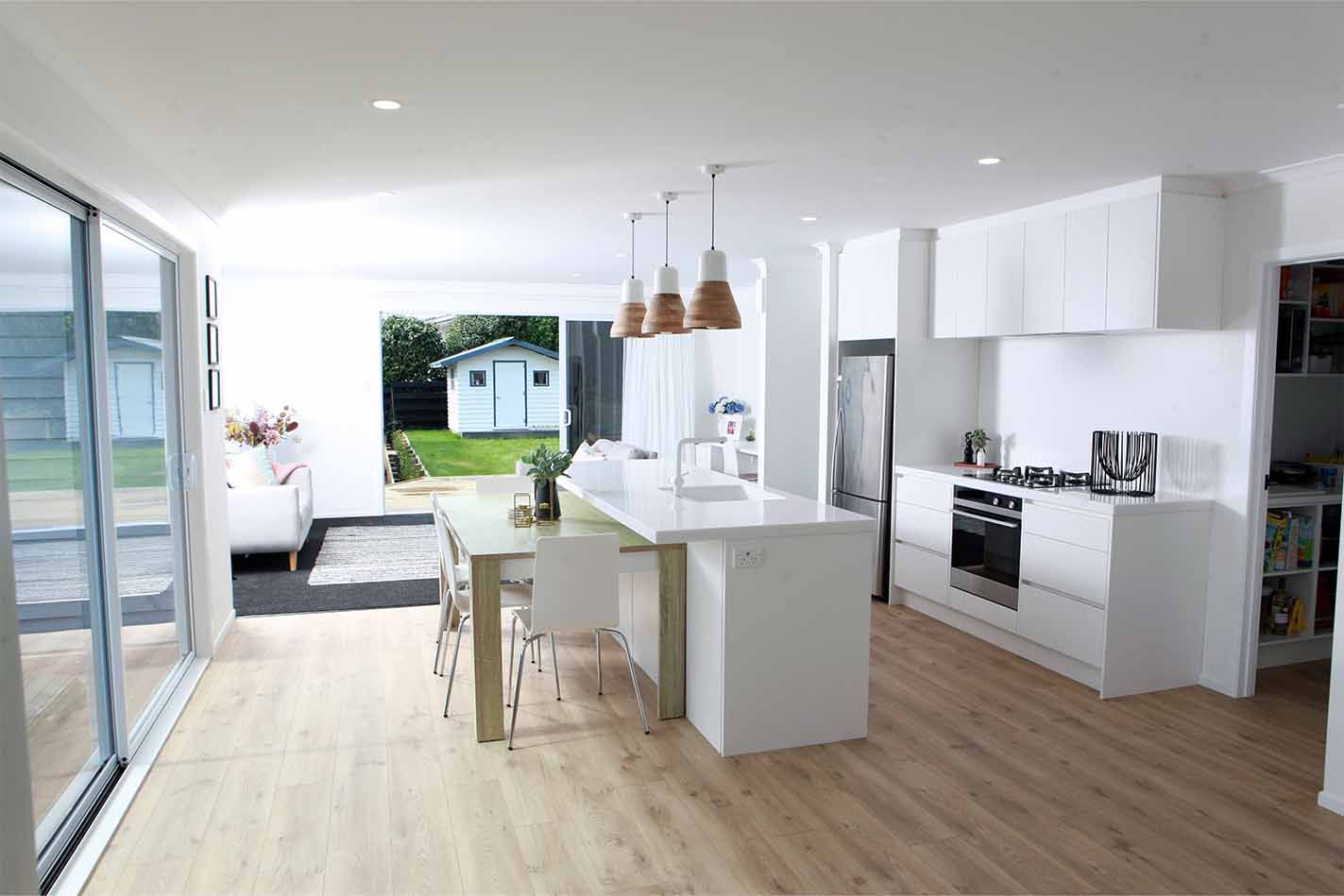 A kitchen with white cabinets and wooden floors and a large island in the middle.