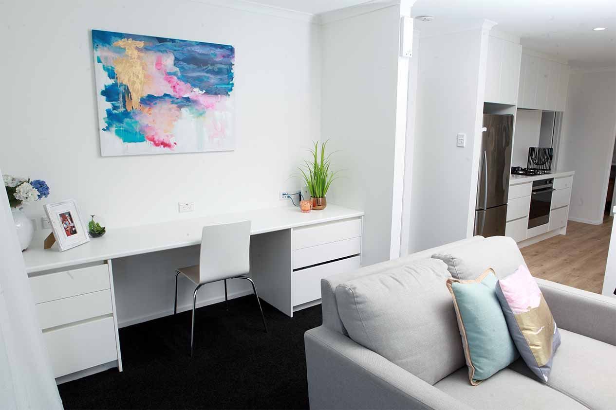 A living room with a couch , desk , chair and painting on the wall.
