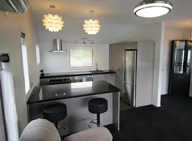 A kitchen with a black counter top and stools