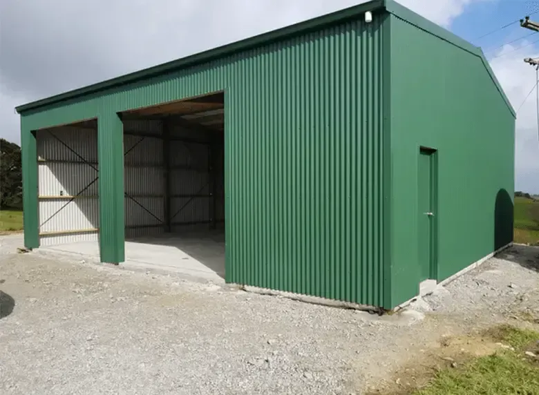 A green metal building with a sliding door