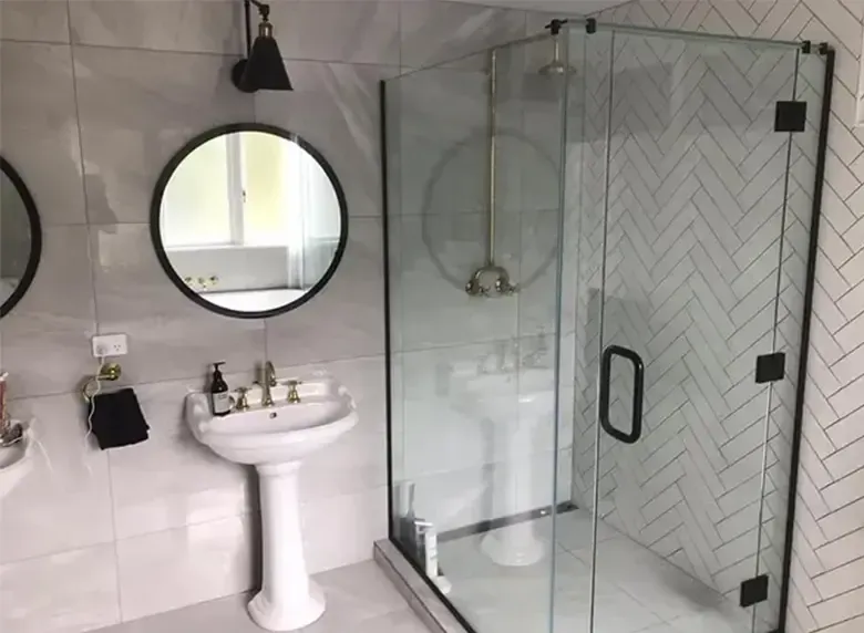 A bathroom with a sink , mirrors , and a walk in shower.