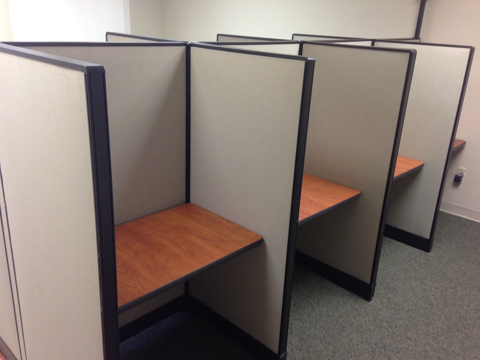 A row of cubicles with wooden desks in an office