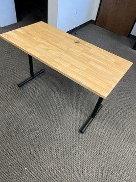 A wooden desk is sitting on top of a carpeted floor.