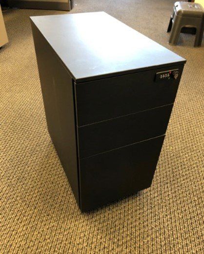 A black filing cabinet is sitting on a carpeted floor.