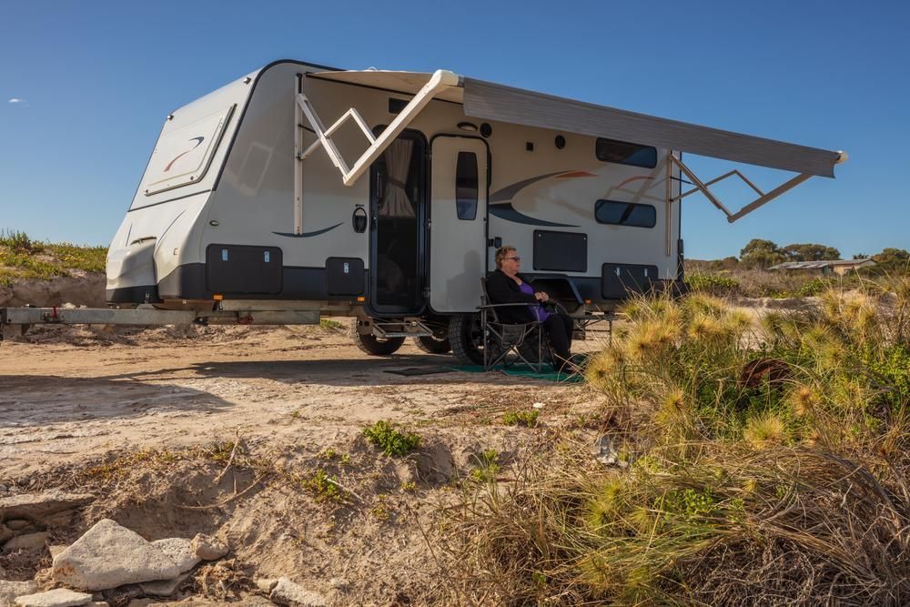 A Woman is Sitting in a Chair in Front of a Camper Trailer — Wheel Alignment Centre In Braitling, NT