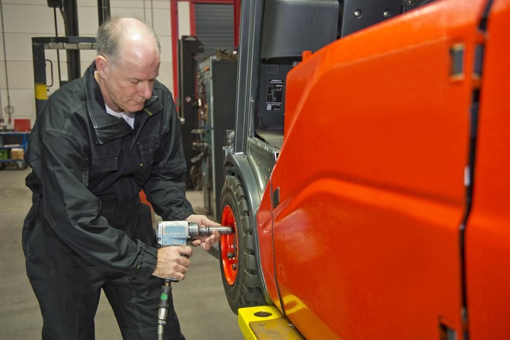 A Man is Working on a Forklift in a Garage — Wheel Alignment Centre In Braitling, NT