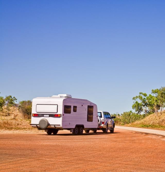 A Truck is Towing a Trailer Down a Dirt Road — Wheel Alignment Centre In Braitling, NT