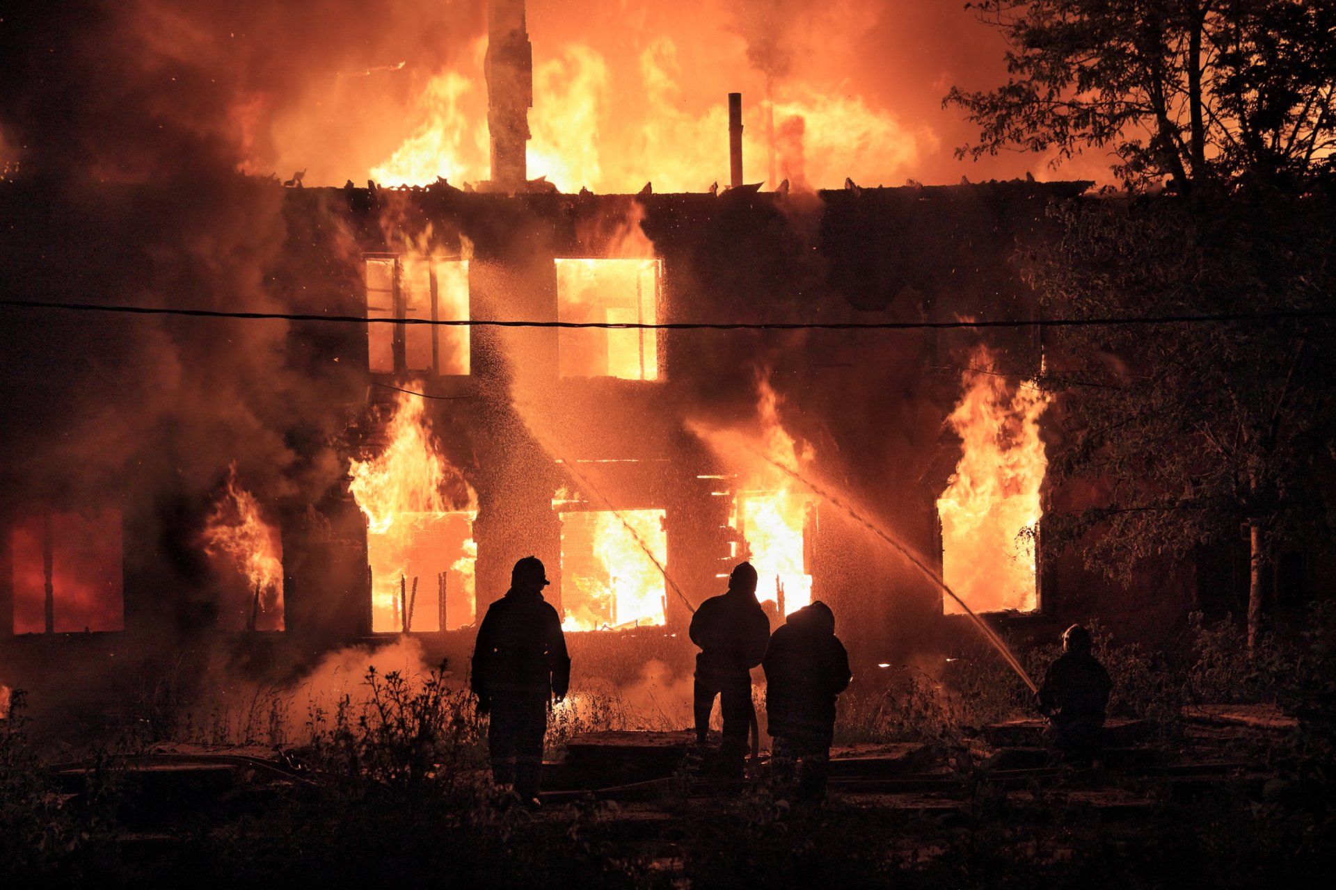 a group of fire fighters are standing in front of a house that is on fire.