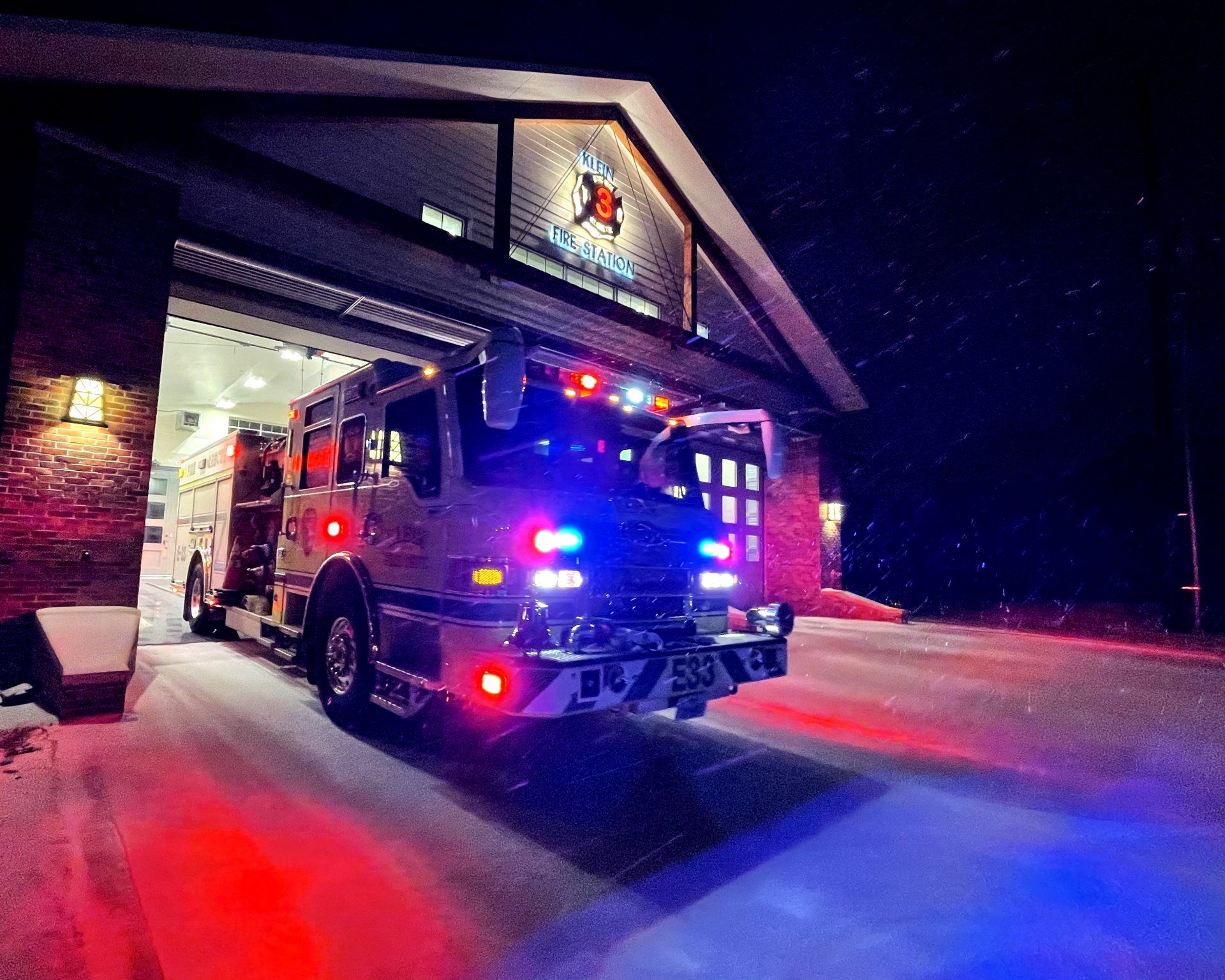 A fire truck is parked in front of a fire station at night.