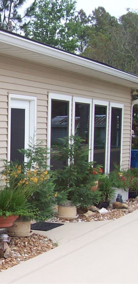 Man in blue shirt and cap installing a window screen outdoors, holding the screen frame.